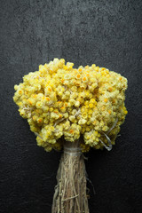 Bouquet of dry immortelle on a black background, vertically.