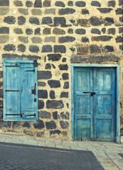 Old  wall with wooden window and worn wooden door.