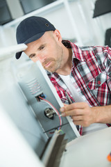 Naklejka na ściany i meble male technician checking refrigerator with screwdriver