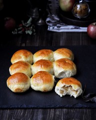 Buns of yeast dough stuffed with apples and raisins. Dark background, fresh apples