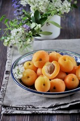 On a wooden table on a platter of fresh apricots with bones, decorated with flowers