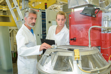 Male and female technicians checking machinery