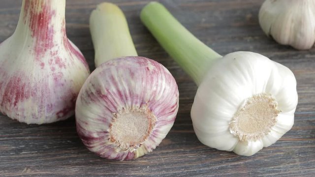 Closeup of fresh garlic bulbs on wooden table. Camera locked down.