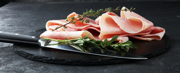 Sliced ham on stone background. Fresh prosciutto. Pork ham sliced. - obrazy, fototapety, plakaty