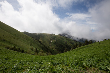 Fototapeta na wymiar The formation and movement of clouds over the summer slopes of Adygea Bolshoy Thach and the Caucasus Mountains