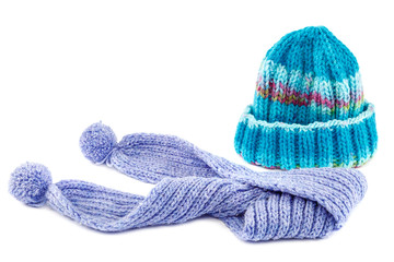 Blue knitted cap and scarf on white background.