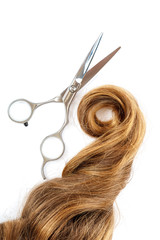 Professional hairdressing scissors and a lock of blond hair.