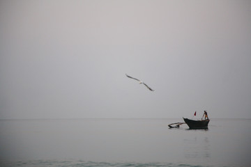 Fototapeta premium Fisherman on an old fishing boat in the calm water of the sea