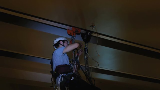 Industrial climber mounts Christmas decorations in the unsupported space in the shopping center