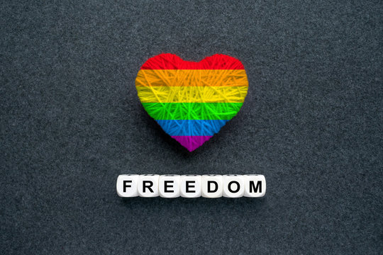 Knitted heart with Lgbt gay rainbow flag and words Freedom on a dark felt background. Multicolored Heart in the gay pride flag. LGBT transgender movement