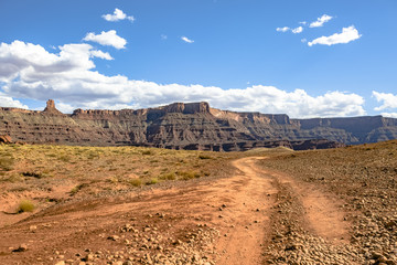 Canyon vies in Moab, Utah seen from the view of off-roading vehicles, trails and puffy white clouds