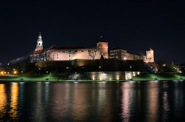 Lights from Wawel Royal castle reflect of the Vistula River in Krakow