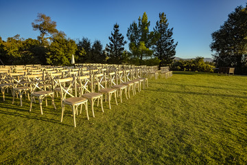 Fototapeta na wymiar Chairs set up on a lawn for a wedding cerimony with no people yet from the front