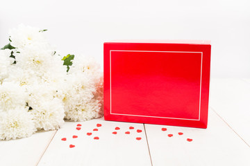 Red gift box with copy space with flowers on wooden table