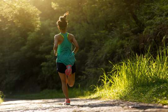 Young fitness woman athlete running on forest trail