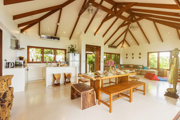 Luxury villa living room with kitchen interior. White walls and wooden furniture