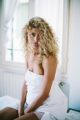 Young curly hair woman waking up on her bed in bedroom. Happy morning, free time