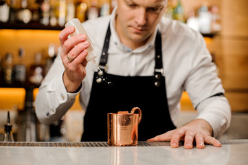 Barman in white shirt pouring alcoholic drink into a cup