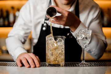 Barman hand pouring a portion of alcoholic drink into a glass