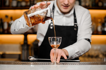 Barman pouring alcoholic drink into a glass