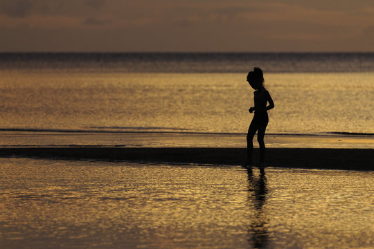 the silhouette photo of asian girl enjoy on the beach with colorful sea in sunrise