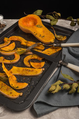 Roasted sliced butternut squash seasoned with salt, sweet pepper, pepper and thyme on baked dish.