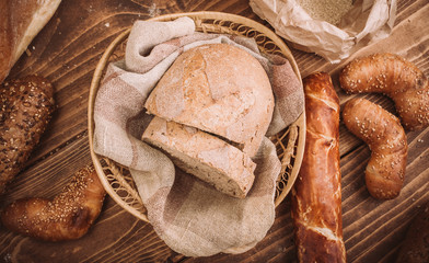Many mixed baked breads and rolls on rustic wooden table