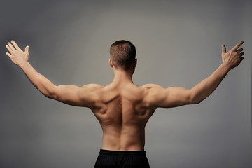 Muscular young bodybuilder on grey background