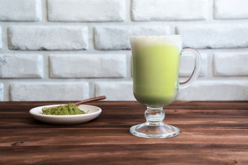 Matcha latte on wooden table. Creamy drink with milk and japanese green tea powder. 