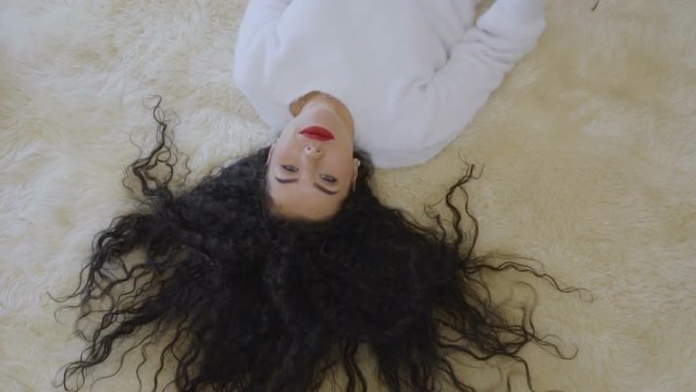 Beautiful curly brunette lays on floor in slowmotion