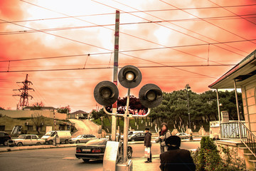 A barrier with a traffic light railroad under a red sky