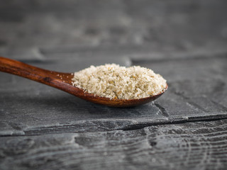 Spoon dark wood filled to the brim with salt with herbs on a dark wooden table.