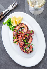 Grilled octopus on white plate serverd with white wine , top view. Seafood