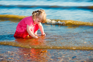 2-3 years old little girl playing with pebbles at the riverbank