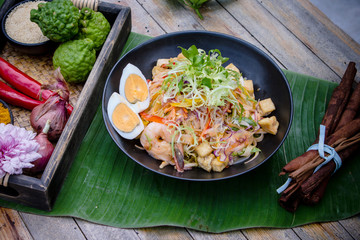 The Art of Thai Healthy Dish - Pad Thai with Prawn Salad with an array of herbs and spices on the wooden board background.