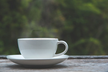 Hot coffee cup on wood table nature blurred background.
