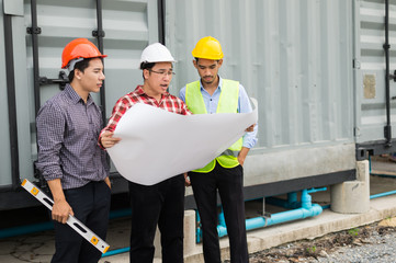 engineer and construction team wearing safety helmet and blueprint on hand. engineer and client working on checking progress of construction site.