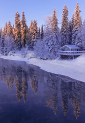 Cabin on river in snowy Alaska