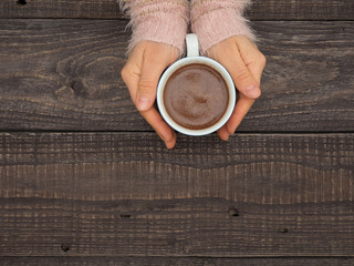 Women's hands hold a mug with hot cocoa