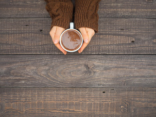 Women's hands hold a mug with hot cocoa