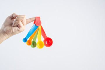 Hand holding set of measuring spoons made of colored plastic