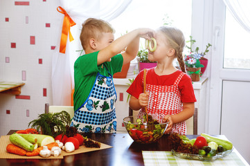 Fun children prepare salad vegetables . Happy kids in the kitchen . The concept of a healthy vegetarian diet