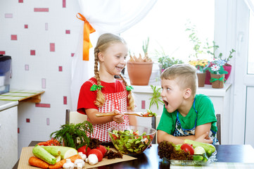 Fun children prepare salad vegetables . Happy kids in the kitchen . The concept of a healthy vegetarian diet