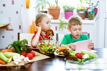 Fun children prepare salad vegetables . Happy kids in the kitchen . The concept of a healthy vegetarian diet