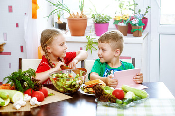 Fun children prepare salad vegetables . Happy kids in the kitchen . The concept of a healthy vegetarian diet