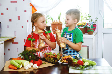 Fun children prepare salad vegetables . Happy kids in the kitchen . The concept of a healthy vegetarian diet
