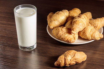 Glass of milk and fresh croissants on wooden table