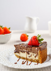 Delicious chocolate cheesecake with strawberry on a table against white wall.