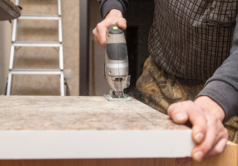 Master cuts wood with a jig saw