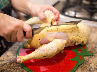 The cook cuts the chicken with a knife
